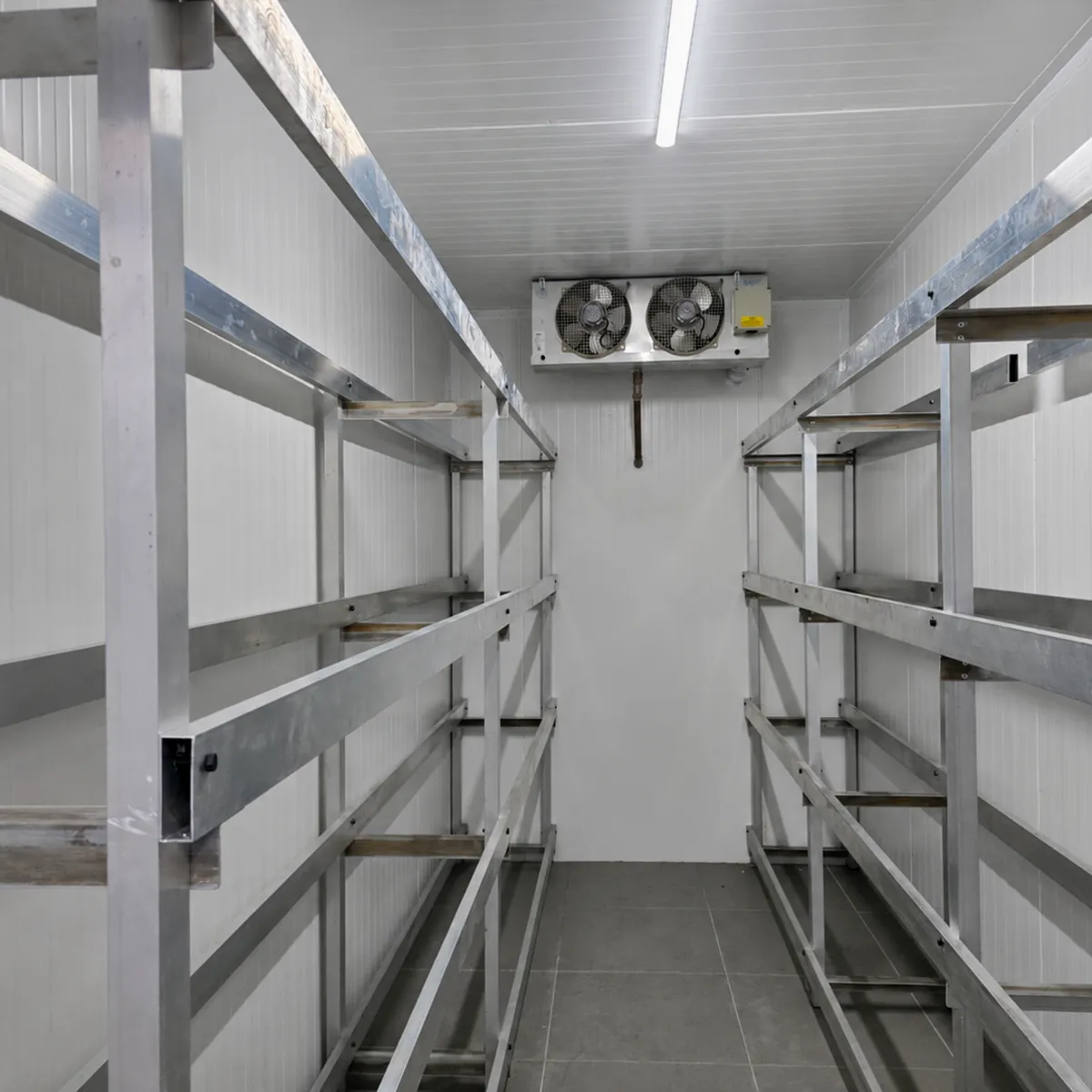 Interior de câmara fria comercial com estantes e evaporador